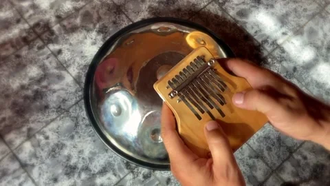 Playing kalimba with handpan in background Stock Footage 168924121