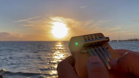 Playing kalimba at sunset Stock Footage 168876501