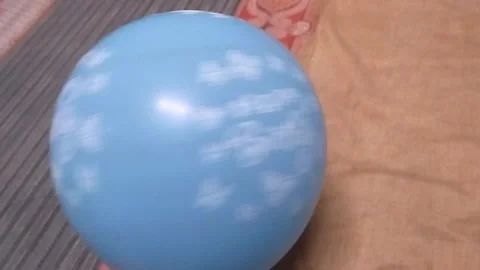Playing with a light blue balloon by moving it using hands Stock Footage 325023873