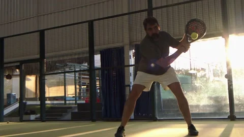 Playing Padel, a man returns the ball after a bounce off the back wall Stock Footage 203834636