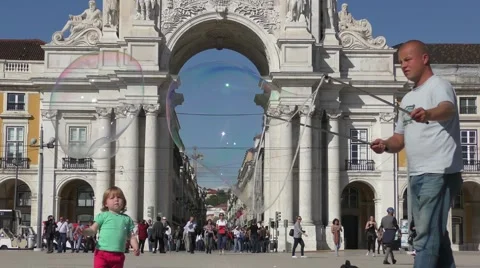 Playing with soap bubbles near Famous arch at the Praca do Comercio Видео 67892676