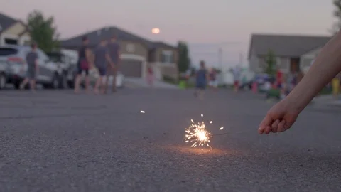 Playing with Sparkler on Ground with People in background Video stock 99457633