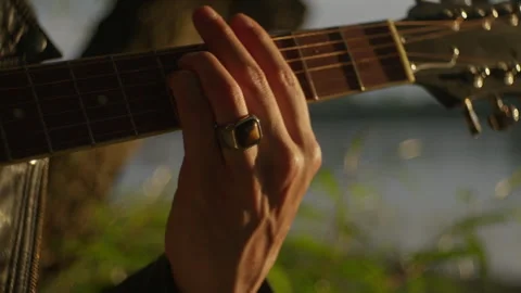 Playing strumming man guitar by the riverside at sunset Stock Footage 319952126
