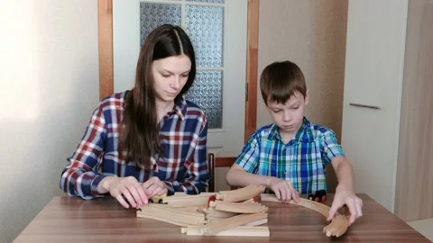 Playing together. Mom and son are building a wooden railway with tunnel sitting Vídeos de archivo 86597857