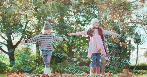 Playing two kids with arms spread at park, in beanies, boots, falling leaves, Stock Photos