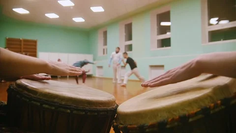 Playing a two musical instruments jembe or atabaque on background male fighter Stock Footage 99039859