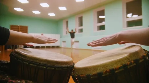 Playing a two musical instruments jembe on background male fighter performs Stock Footage 99041508