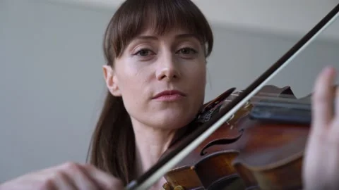Playing the violin, looking into the camera, turning a page with sheet music. Stock Footage 155111781