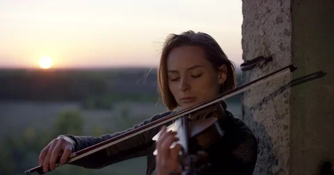 Playing violin in ruined building with sunset 4K. Video stock 80468760