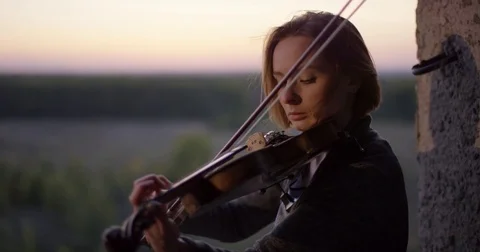 Playing violin in ruined building with sunset 4K. Stock Footage 80469841