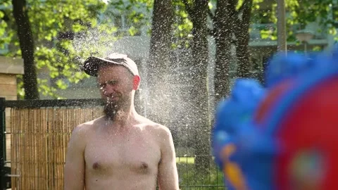 Playing with water gun, man gets unexpectedly splashed by water in the face 動画素材 243731419