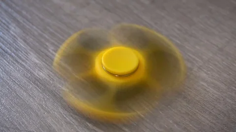 Playing with the yellow Fidget Spinner. Toy spinner Stock Footage 78812903