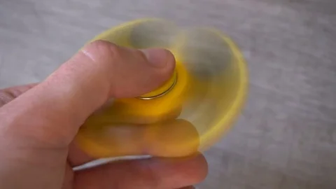 Playing with the yellow Fidget Spinner. Toy spinner in hand Vídeo Stock 78814159