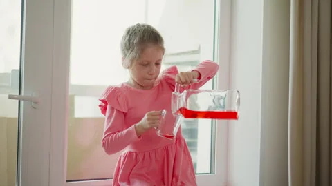 Playmate Seated By Kitchen Window Pouring Drink After Playtime On Sunny Day Stock Footage 307976013