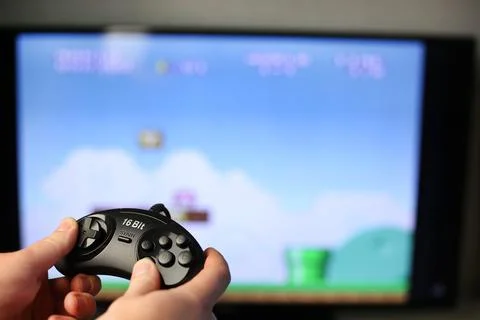 Plays a retro game on the TV while holding classic black joystick Stock Photos
