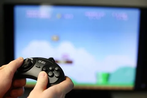 Plays a retro game on the TV while holding classic black joystick Stock Photos