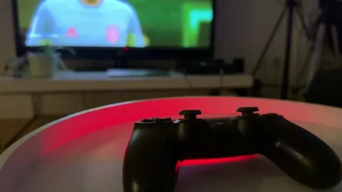 Playstation control in the foreground and the blurred tv in the background Video stock 258362096