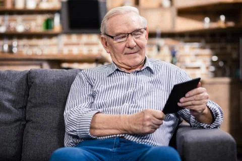 Pleasant aged man reading an e book Stock Photos