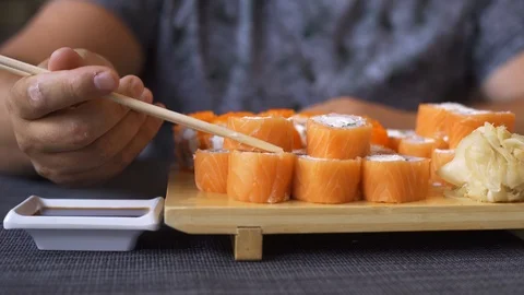 Pleasant chubby man with a beard in a sushi bar, eating rolls. Does not know how Video stock 115336856