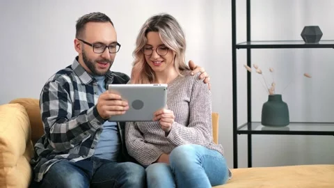 Pleasant couple hugging talking use tablet pc together relaxing on couch. Medium Stock Footage 151784546