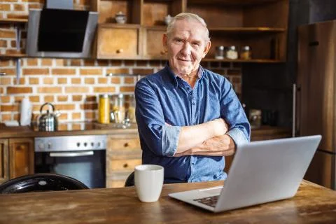 Pleasant eldelry man standing in the kitchen 스톡 사진