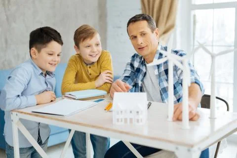 Pleasant father explaining construction of wind turbines to his sons Stock Photos