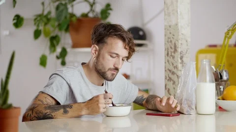 Pleasant Hispanic man using smart mobile device eating at morning breakfast time Stock Footage 108795789