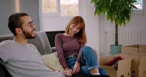 Pleasant Hispanic pair resting after relocation in new living room together Video stock 123667422