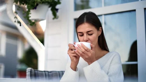 Pleasant lady drinking hot tea enjoying fragrance on terrace. Medium close up Stock Footage 143592562