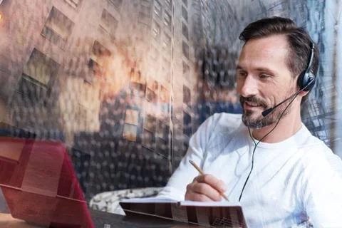 Pleasant man watching video tutorial and making notes 写真素材