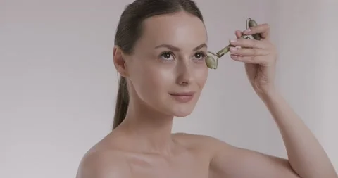 Pleasant model with bare shoulder using facial stone roller Stock Footage 158731874