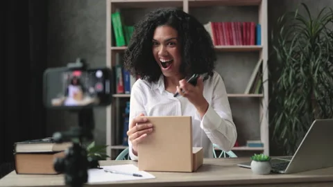 Pleasant multinational woman while opening parcel box with new smartphon 動画素材 221281380