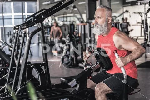 Pleasant senior male is having intensive workout in athletic center Stock Photos