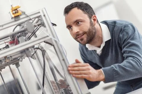 Pleasant young engineer moving 3D printer Stock Photos