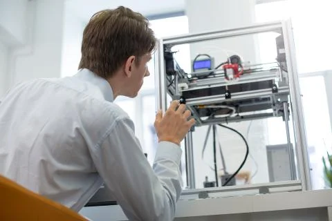 Pleasant young intern learning 3D printers work algorithm Stock Photos