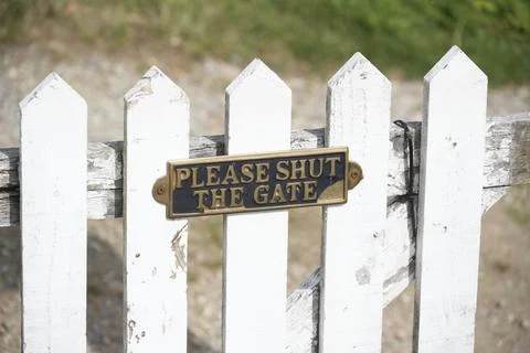 Please close gate sign on white wooden fence Stock Photos