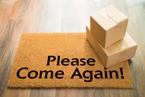 Please Come Again Welcome Mat On Wood Floor With Shipment of Boxes Stock Photos