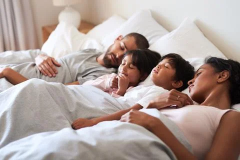 Please dont wake us up. a beautiful young family of four fast asleep in bed Stock Photos