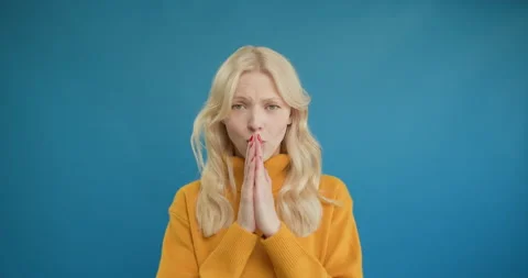 Please, I need. Cute beseeching blonde woman in yellow sweater holding hands in Stock Footage 150905268