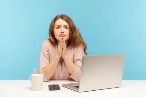Please, need your help! Young woman employee sitting at workplace and holding Stock Photos
