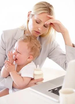 Please. Stop. Crying.. An overwhelmed mom sitting in front of the computer wi Stock Photos