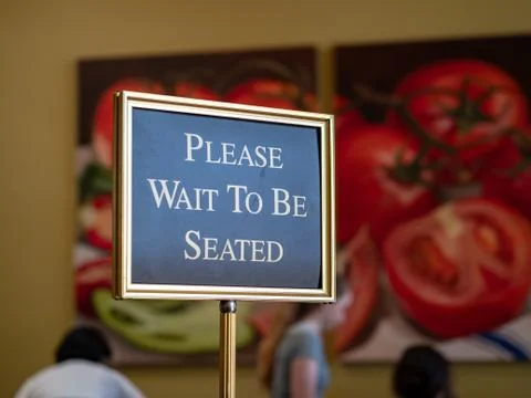 Please wait to be seated sign standing at the front of a restaurant Stock Photos