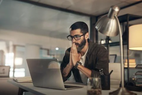 Please work, please work. a young businessman looking anxious while using a Stock Photos