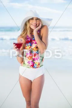 Pleased blonde model in swimsuit holding a cocktail Stock Photos