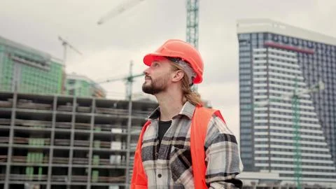 Pleased builder walking through building site during work break Stock Photos