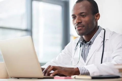 Pleased dark-skinned practitioner reading news Stock Photos