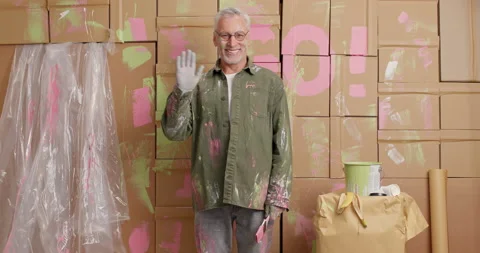 Pleased grey haired man waves palm and greets someone happy doing walls Stock Footage 144915241