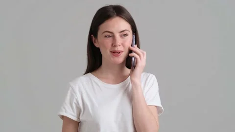 A pleased woman wearing basic T-shirt is talking her smartphone Video stock 154946017