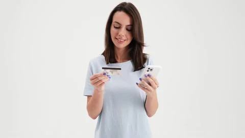 A pleased woman wearing basic t-shirt is holding a credit card Stock Footage 157867250