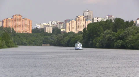 Pleasure boat floats down the river on a summer forest and the city background Stock Footage 39664845